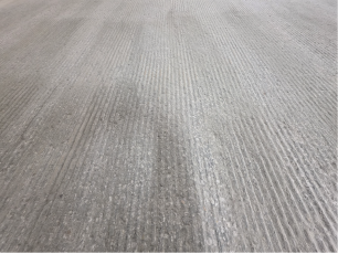 Eingeweichte Frässpuren in einem grauen Betonboden.