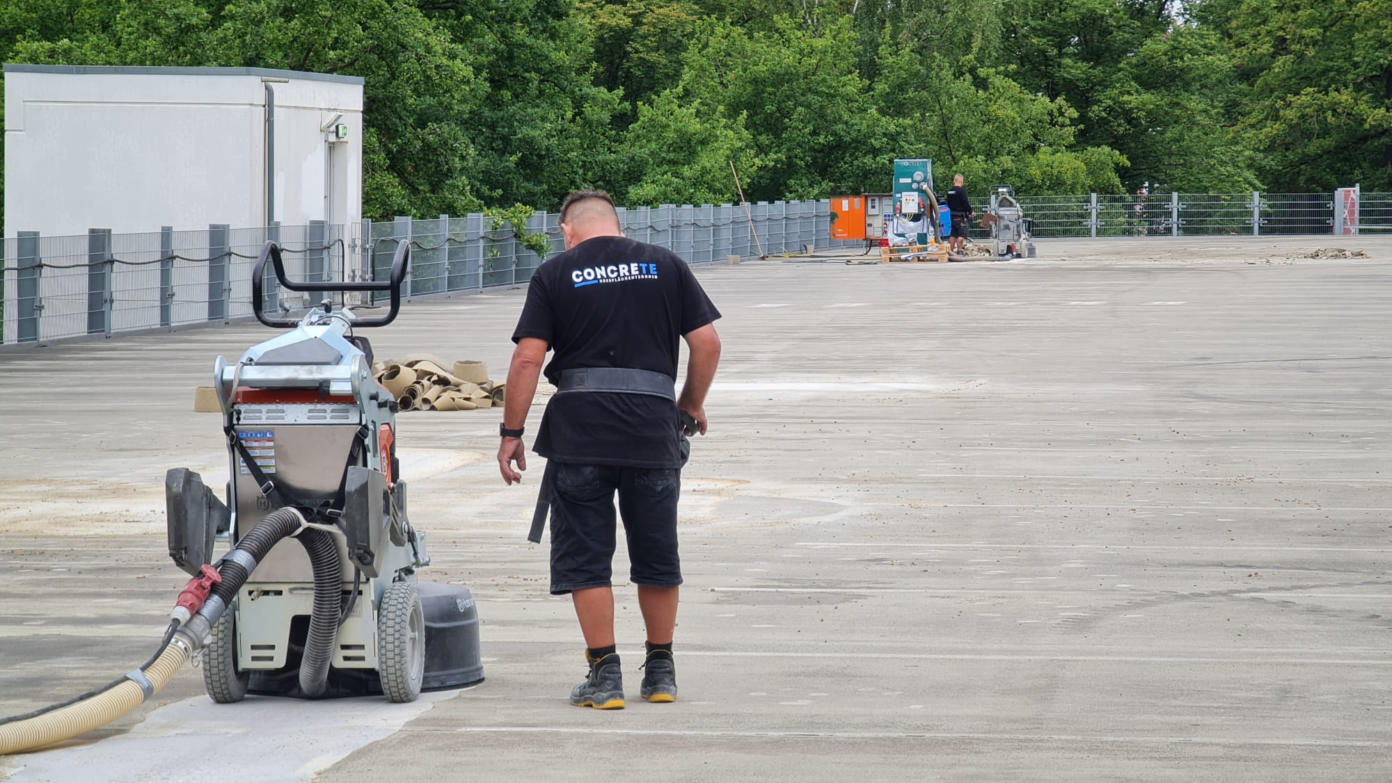Oberflächenbearbeitung eines Parkdecks mit einer motorisierten Schleifmaschine inklusive angeschlossener Staubabsaugung